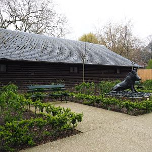 Gardens, bench and Wild boar statue next to historical bison barn, 2023-04-08