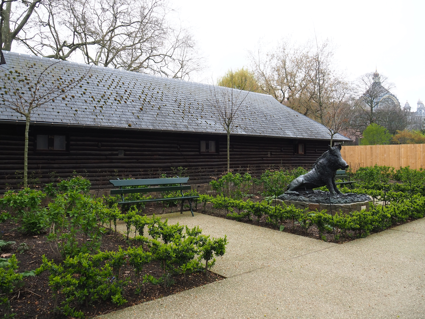 Gardens, bench and Wild boar statue next to historical bison barn, 2023-04-08