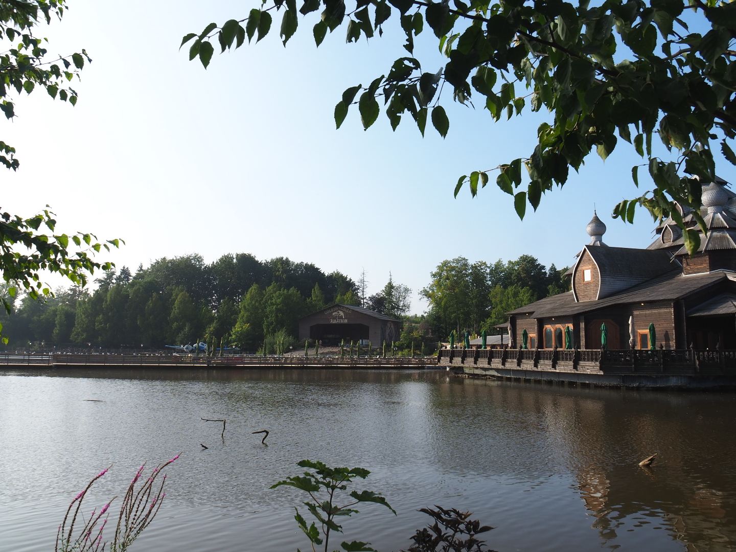 VIew over lake with Russian restaurant L'Izba, pontoon terrace and theming hangar, 2021-09-02